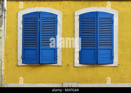 Closed blue window shutters and a yellow wall in Verdun, France Stock Photo