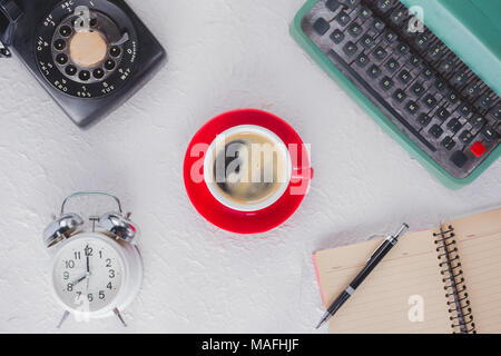 A cup of coffee with typewriter , alarm clock , telephone , notebook . top view image Stock Photo