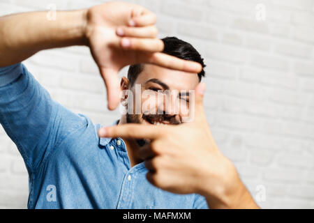 Portrait of happy man smiling. Italian guy looking at camera and doing hand gesture for taking picture. Stock Photo