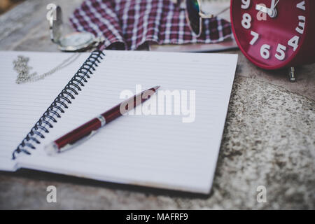 Notebook and pen with alarm clock, in vintage tone effect. Stock Photo