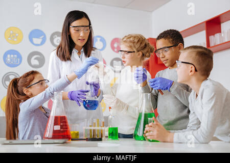 Group of students and their teacher conducting chemical experiment Stock Photo