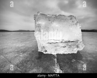 Melting pieces of chopped ice blocks. Strong colorful backlight shine deep cracks, low angle view. Far flat horizon. Stock Photo
