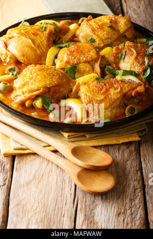 Spicy chicken stew with salted lemons, onions and green olives close-up on a plate on a table. vertical Stock Photo