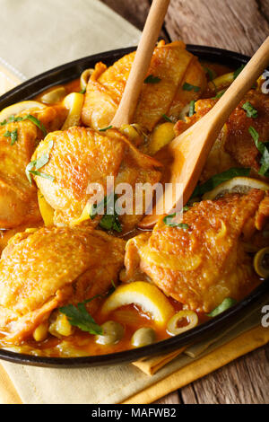 tajine chicken with salted lemons, onions and green olives close-up on the table. vertical Stock Photo