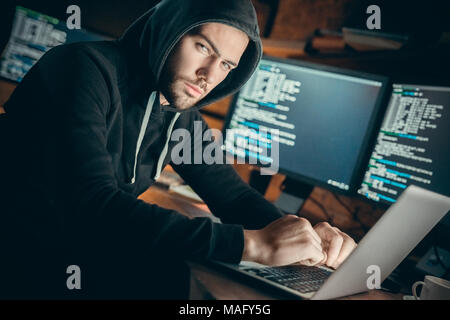 Young man financial hacker at office sitting at table looking camera careful Stock Photo