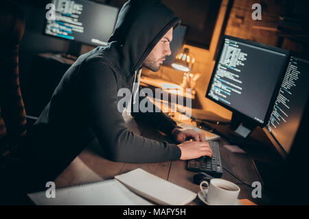 Young man financial hacker at office sitting at table typing code to unlock data concentrated Stock Photo