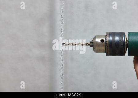 Worker drilling a hole into the wall with an electric drill. Stock Photo
