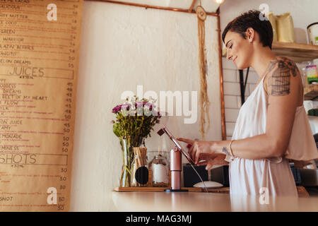 Woman standing at the billing counter of her restaurant. Restaurant owner operating the billing machine. Stock Photo