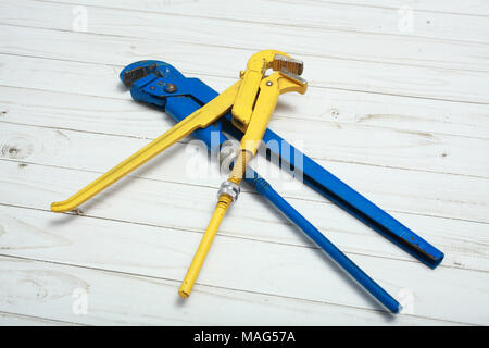Two adjustable pipe wrench, pliers, wrenches or plumbing tool, on white wooden surface. Stock Photo