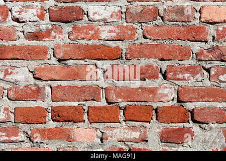 Front view of wall constructed from red and orange bricks with concrete. Stock Photo