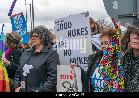 Aldermaston, UK. 1st Apr, 2018. People listen to speeches as CND celebrates the 60th anniversary of the first Aldermaston march which mobilised thousands against the Bomb and shaped radical protest for generations. Their protest outside the Atomic Weapons Establishment included a giant, iconic peace symbol, speeches, including by some of those on the original march, singing and drumming and celebrated the UN treaty banning nuclear weapons. Campaign to abolish nuclear weapons. Credit: Peter Marshall/Alamy Live News Stock Photo