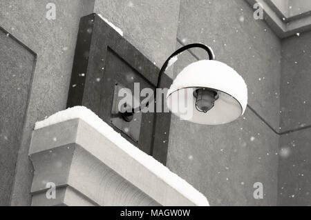 Snow falling around a snow covered light in black and white. Stock Photo