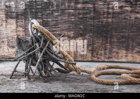 Two-way steel search magnet with rusty nails and old rope on wooden table, text place Stock Photo