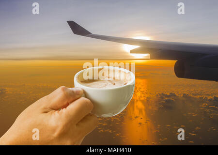 cup of coffee in the hands on Airplane's wing against golden sunlight in early morning background Stock Photo
