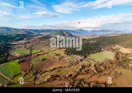 Hot air balloon flying with croscat open volcano and mountains on the background, cloudy day, Olot, Catalonia, Spain Stock Photo
