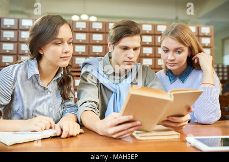 College students reading textbook in library Stock Photo
