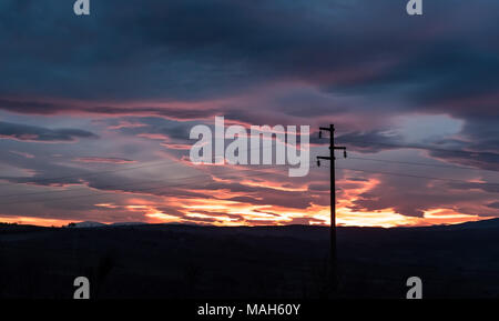 Power line - Single column in front of dramatic sky at sunset, near twilight Stock Photo