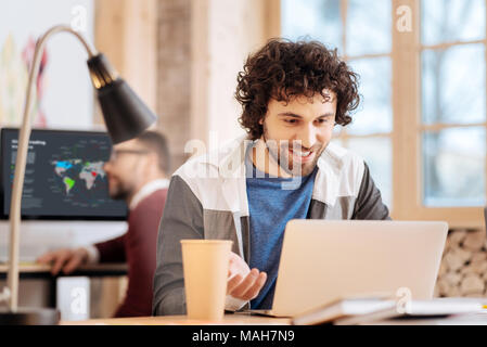 Delighted young man working on his laptop Stock Photo