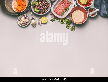 Bowls with ingredients for balanced one pan meal with beans, minced meat, rice and cut vegetables on gray background, top view, border or food backgro Stock Photo