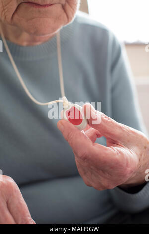 Close Up Of Unwell Senior Woman Holding Personal Alarm Button At Home Stock Photo