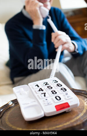 Close Up Of Senior Man Using Telephone With Oversized Keypad At Home Stock Photo