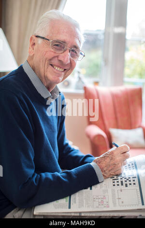 Portrait Of Senior Man Doing Crossword Puzzle At Home Stock Photo
