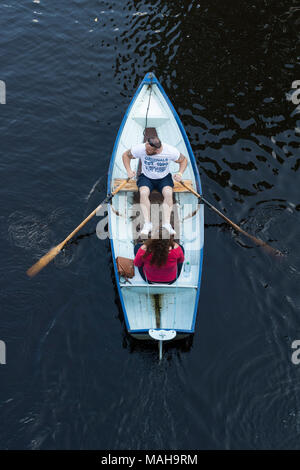 Overhead view of 2 people (man & woman in couple) sitting, relaxing & boating in rowing boat on River Nidd in summer - Knaresborough, England, UK. Stock Photo