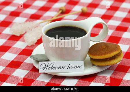 Welcome home card with cup of coffee and Japanese cookie on checkered cloth Stock Photo