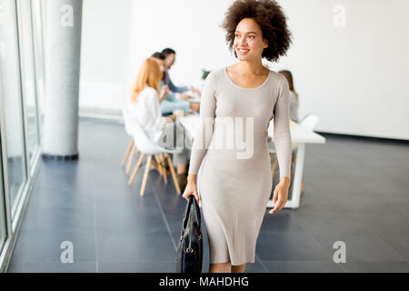 View at business people discussing a strategy and working together in office while young businesswoman leaving office Stock Photo