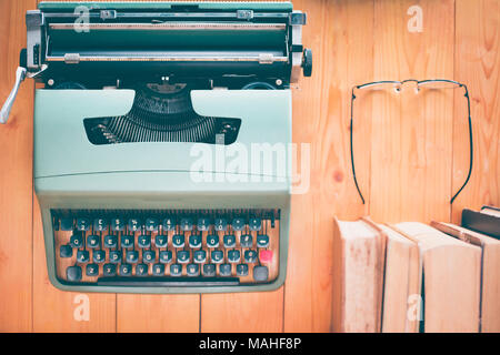 Retro typewriter and old vintage books with reading glasses on wooden table Stock Photo