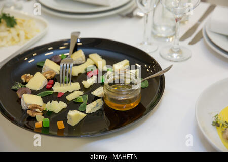 Cheese plate. Assortment of cheese with walnuts, bread an honey on stone slate plate at the buffet or banquet Stock Photo