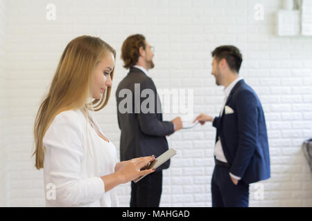 Businesswoman using digital tablet while coworker interacting in the background in the office Stock Photo