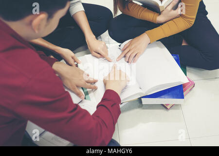 Group of happy students with books talking and preparing to exam in library. Education concept. Stock Photo