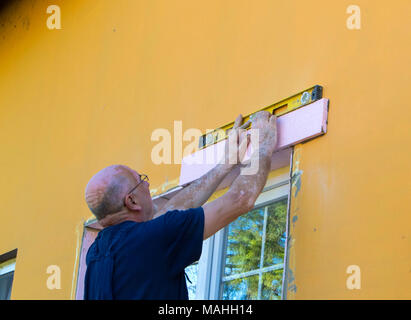 The worker measures the window. Installing a new window and finishing works around it Stock Photo