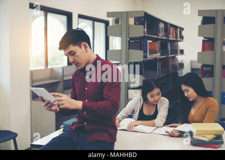 Young students doing using tablet pc at library. Stock Photo