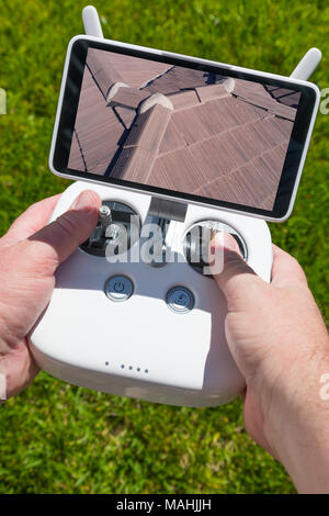 Hands Holding Drone Quadcopter Controller With Residential Roof Image on Screen. Stock Photo