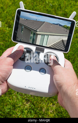 Hands Holding Drone Quadcopter Controller With Residential Roof Image on Screen. Stock Photo