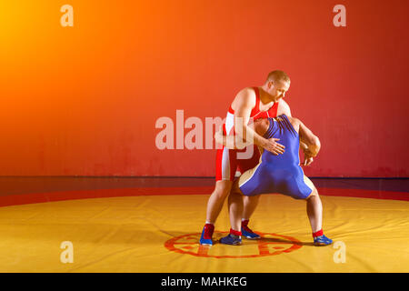 Image of Two Strong Men In Blue And Red Wrestling Tights Are Wrestlng And  Making A Suplex Wrestling On A Yellow Wrestling Carpet In The Gym. Wrestlers  Doing Grapple.-BN493615-Picxy