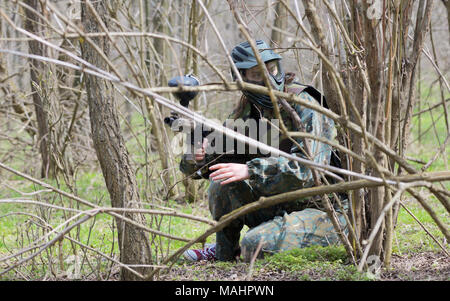 Paintball player under attack in forest Stock Photo