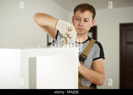 Worker putting screw in white cabinet. Carpenter service theme Stock Photo