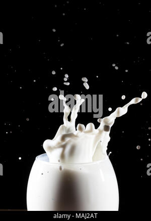 Milk/white liquid splash from glass on black background Stock Photo