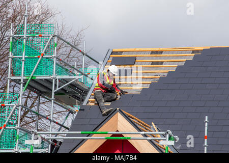 Roof tiler fitting tiles along roof edges on a new build house UK Stock Photo