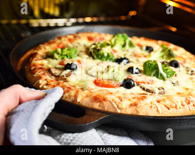 Homemade pizza. Vegetarian pizza in a pizza pan,vegetable pizza with broccoli, mushrooms, tomatoes and olives. Pizza baking scene. Stock Photo