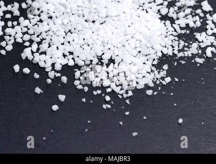 Sea salt on a black background or slate plate. Natural salt, cooking ingredient, close-up shot on black. Stock Photo
