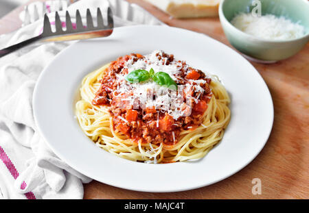 Delicious pasta meal, spaghetti bolognese on a white plate. Pasta Dish, traditional italian food with parmesan cheese, minced meat and basil leaf. Stock Photo
