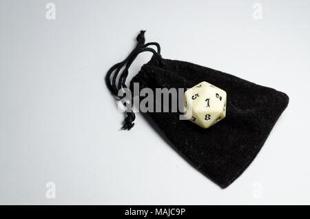 white twenty-sided dice on a small black purse on a white background. Dice of role playing game Stock Photo