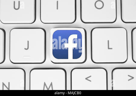 Kiev, Ukraine - May 06, 2016: Facebook logo printed on paper and placed on white computer keyboard. Facebook is a well-known social networking service Stock Photo