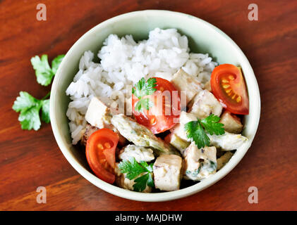 Delicious tofu dish with fresh tomatoes and parsley in a bowl. Rice dish, vegan food or vegetarian meal. Stock Photo