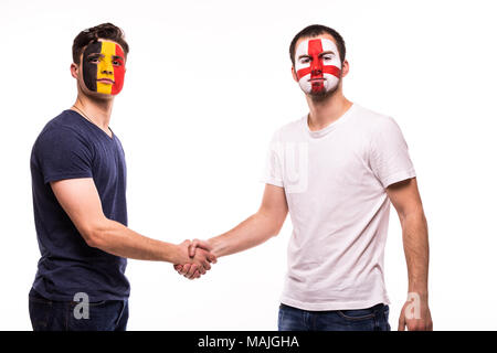 Football fans of Belgium and England national teams with painted face shake hands over white Stock Photo