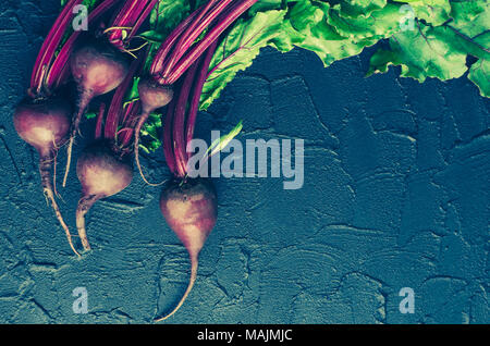 Pile of homegrown organic young beets with green leaves on dark stone table. Fresh harvested beetroots on black concrete background with place for tex Stock Photo